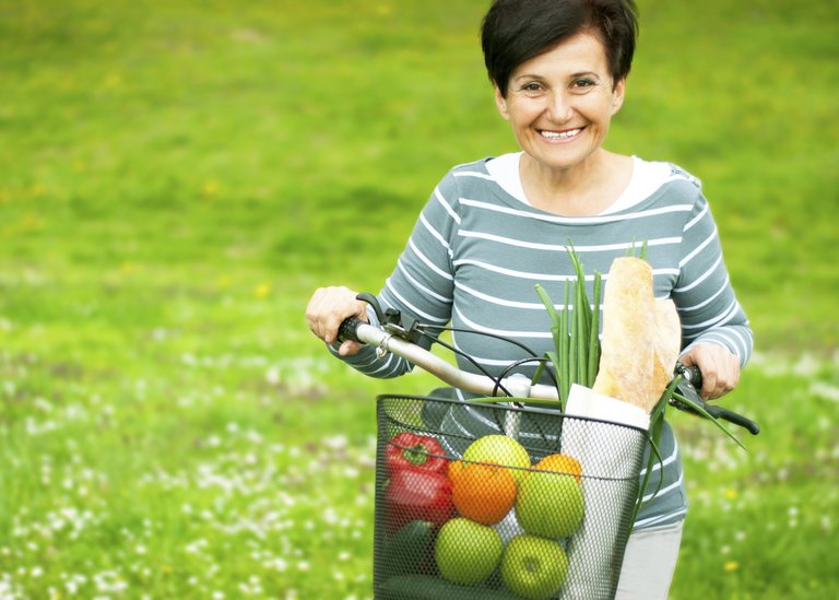 [Translate to South Africa English:] Woman on a bike with healthy food in the basket